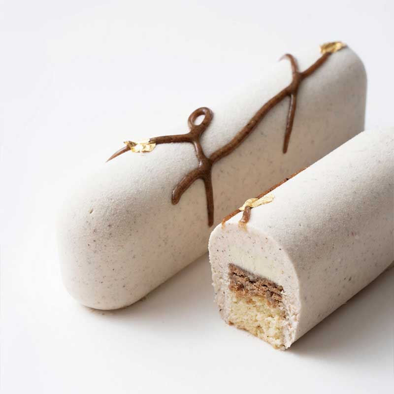 Two cylindrical pastries with a chocolate drizzle on a white background