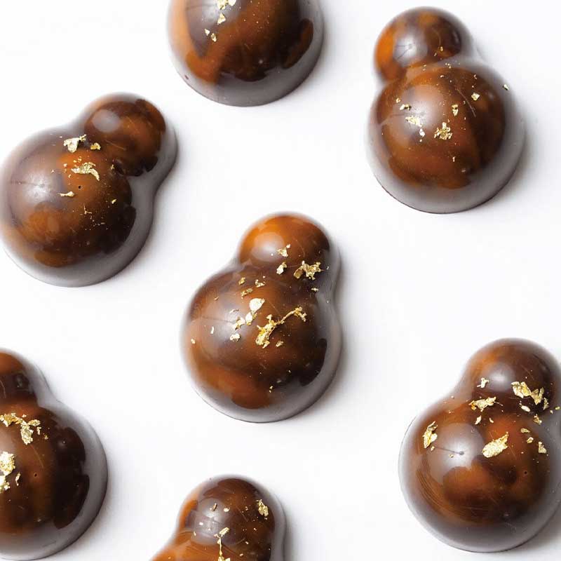 Chocolate truffles with gold flakes on a white background