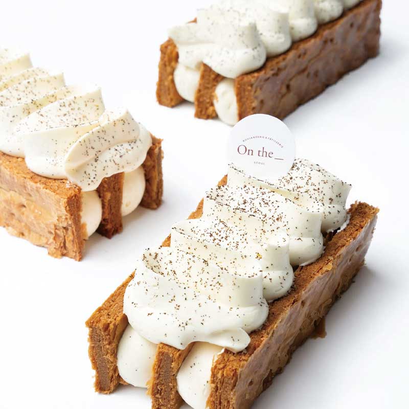 Three dessert bars with white cream and brown cookie-like crust on a white background