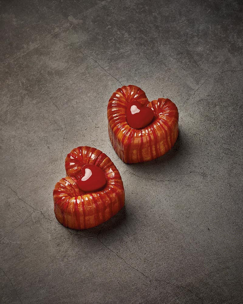 Two heart-shaped croissaint on a gray textured surface