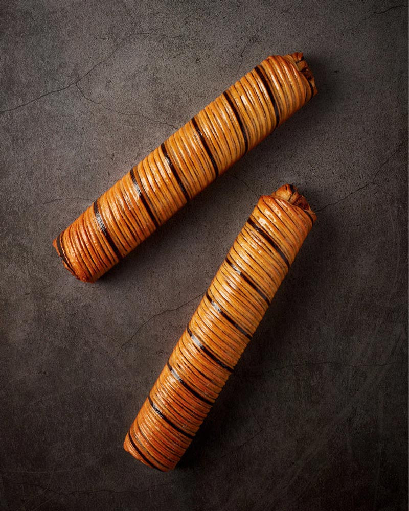 Two wooden rolling pins croissaint on a dark surface